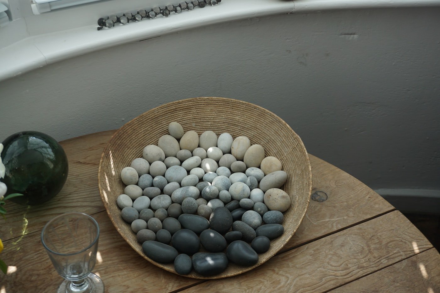 River stones resting in a shallow bowl on warm wood